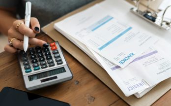 a women holding a pen while using a calculator