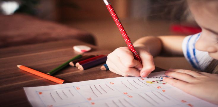 a girl child sitting at a table writing