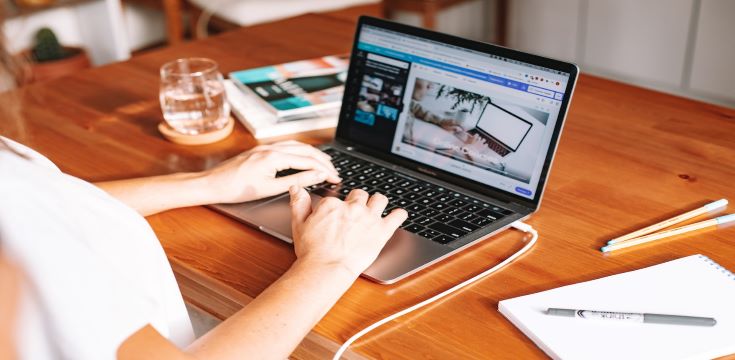 Person Using Laptop on Wooden Desk