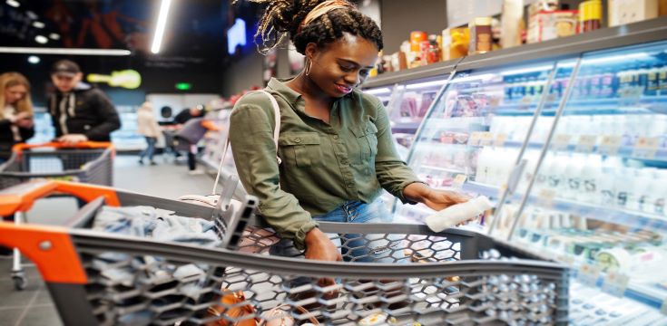 african-woman-with-shopping-cart-choose-yogurt-bottle-from-fridge-supermarket