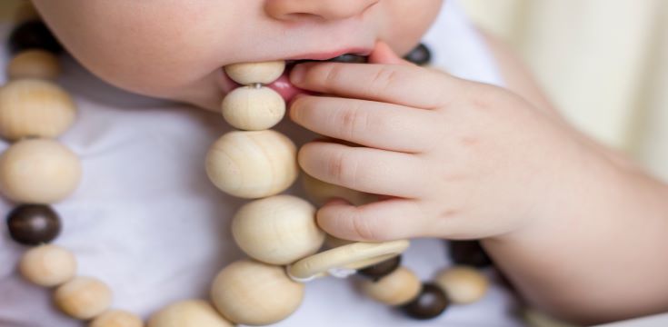 closeup-baby-gnawing-modern-wooden-eco-friendly-teething-necklace