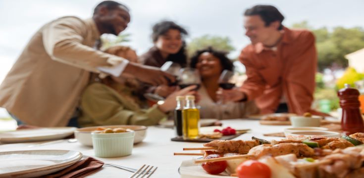 friends-drinking-wine-eating-barbeque-during-outdoor-party