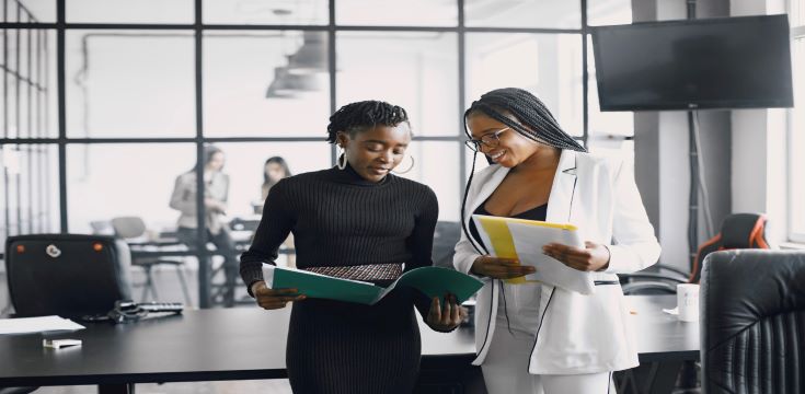 business-women-talking-near-desk-during-coffee-break-hallway-big-corporation