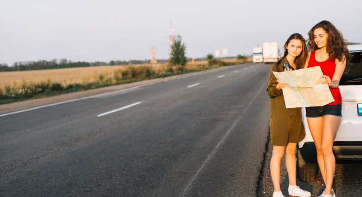 women-standing-near-white-car-with-map