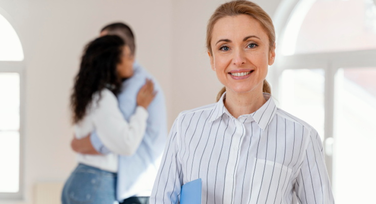 front-view-smiley-female-realtor-with-young-couple-embracing-background