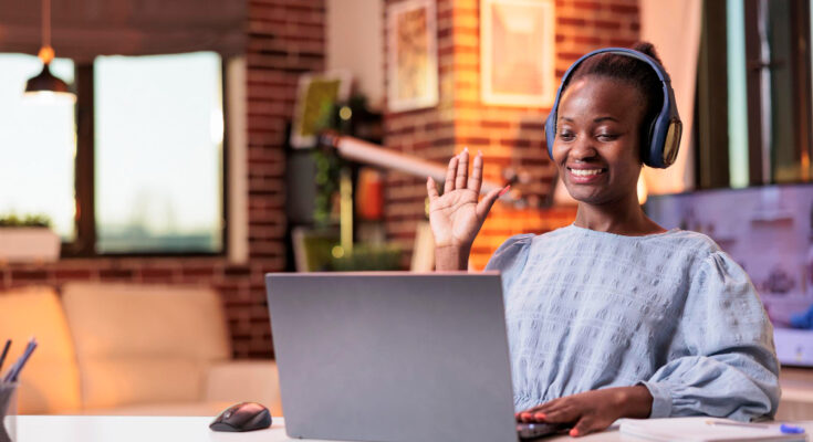 smiling-african-american-female-remote-worker-greeting-colleagues-videocall-modern-home-office-videoconference-meeting-with-company-team-businesswoman-headphones-teleconference